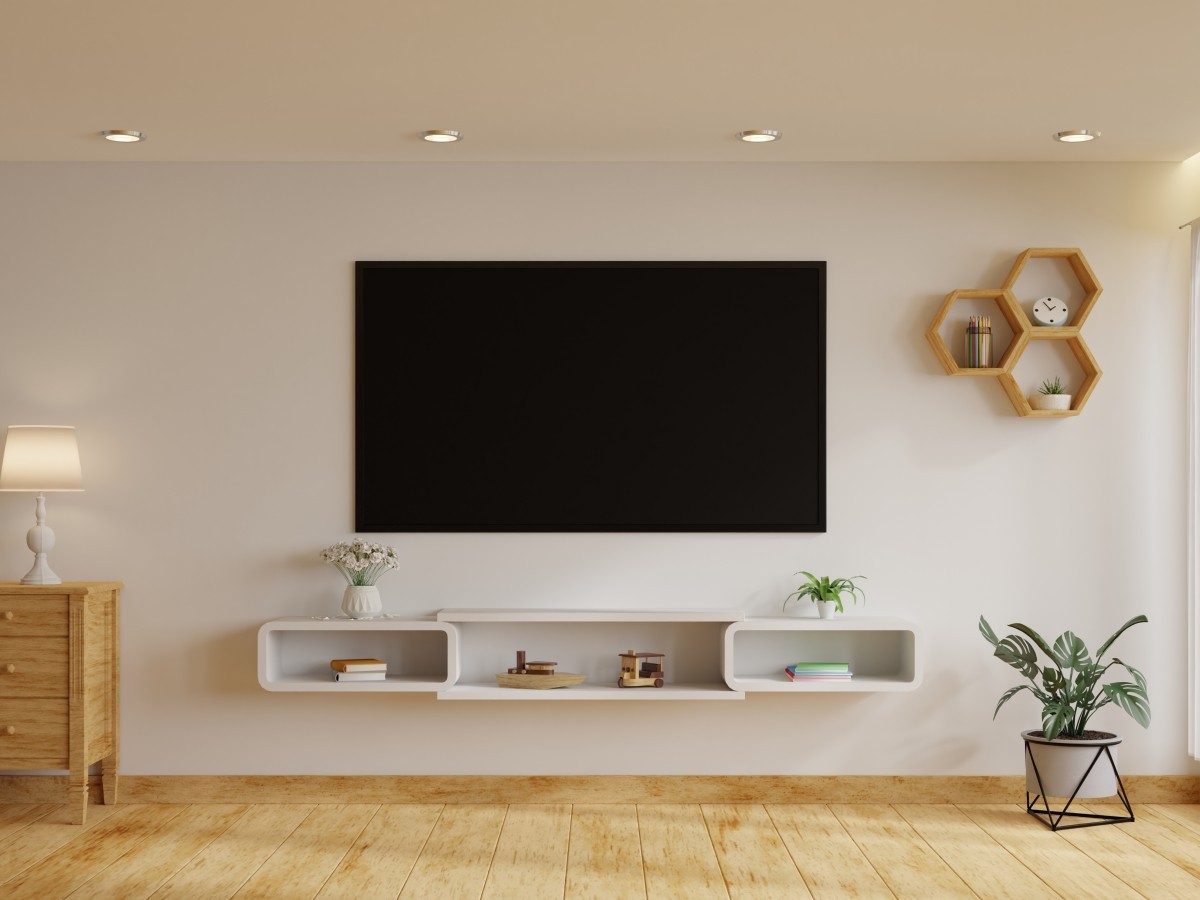 salón con pared blanca y suelo en madera con tv colgada